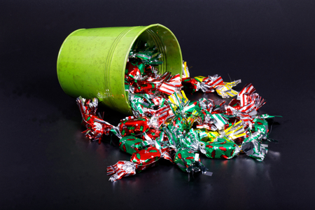 Colorful candy and green bucket on black backgroundの写真素材