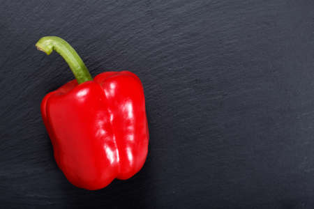 Organic red bell pepper on black slate stone plate with copy spaceの写真素材