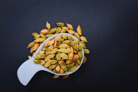 Healthy Food concept Aroma Spice dried Cardamoms in ceramic cup on black slate background with copy for textの写真素材