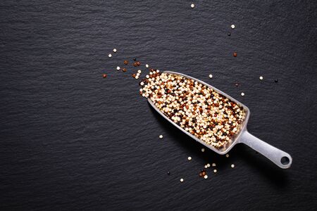 Healthy food  concept Organic raw Quinoa grain mix of 3 colours white, red and black in white ceramic cup on black slate stone plate with copy spaceの写真素材
