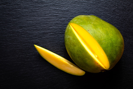 Top view green mango on black slate stone boardの写真素材
