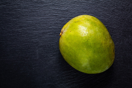 Top view green mango on black slate stone boardの写真素材