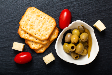Food Appetizer Olives cheese, tomatoes and cracker on black slate board with copy spaceの写真素材