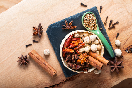 Exotic herbal Food concept Mix of the organic Spices cinnamon stick, cardamom pods, chili, star anise and coriander seedsin wooden background with copy spaceの写真素材