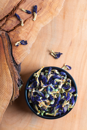 Food concept dry Butterfly pea flower for make the herbal tea in ceramic cup on wood boardの写真素材