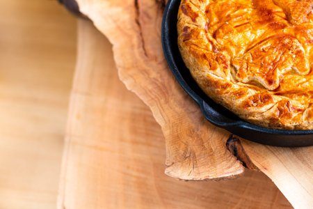 Food concept homemade pork pie or meat pie in cast Iron Skillet and stone plate on wooden background