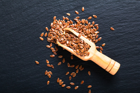 Healthy food concept Organic Flax seeds in wood scoop on black slate board with copy spaceの写真素材