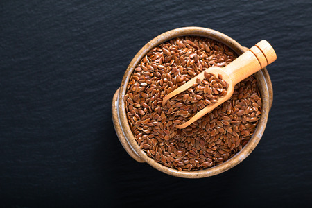 Healthy food concept Organic Flax seeds in ceramic bolw on black slate board with copy spaceの写真素材