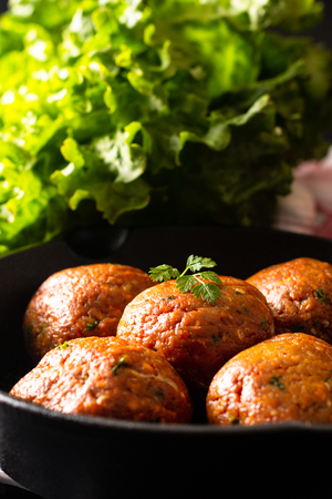 Food Homemade raw organic spicy meatball in iron cast on black backgroundの写真素材