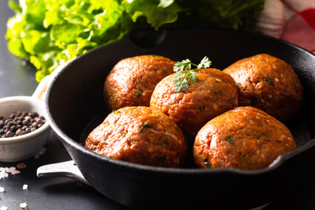 Food Homemade raw organic spicy meatball in iron cast on black background