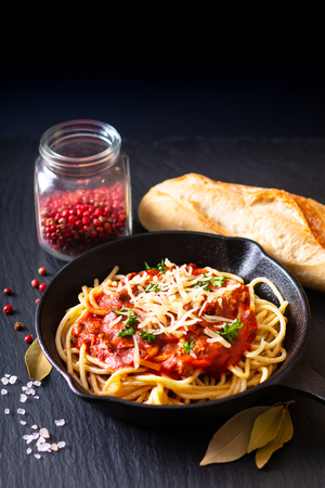 Food concept Homemade spaghetti bolognese in iron cast on black slate stone background with copy spaceの写真素材