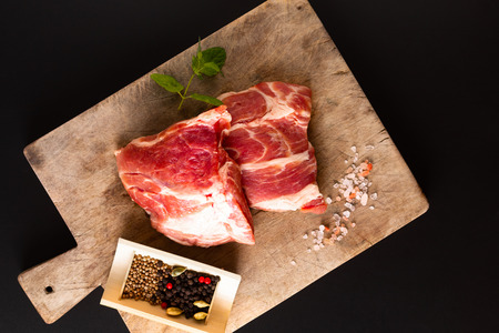 Food concept piece boneless Pork collar on cutting board with spice on black background with copy spaceの写真素材