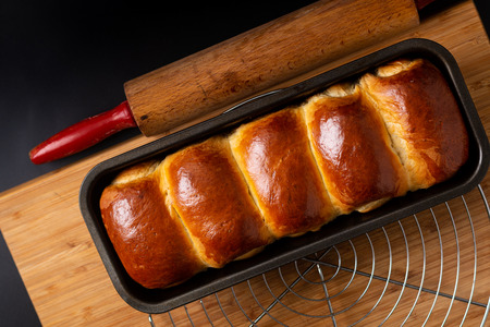 Food Baking concept Fresh baked organic homemade soft milk loaf bread in loaf pan on wooden board with copy spaceの写真素材