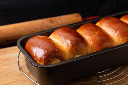 Food Baking concept Fresh baked organic homemade soft milk loaf bread in loaf pan on wooden board with copy spaceの写真素材