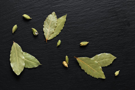 Food Green background concept organic dried bay leaf with cardamom pods on black slate stone with...