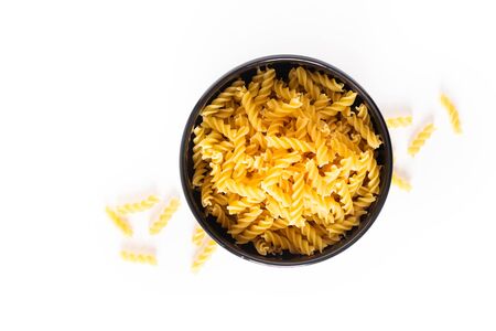 Food concept raw organic Italian Fusili pasta in black bowl isolates on white with copy spaceの写真素材