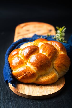 Homemade food concept fresh baked bread braid challah or brioche on black slate stone with copy spaceの写真素材