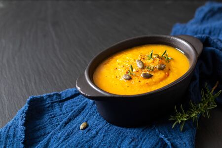 Healthy food concept Warm mix vegetable soup and pumpkin seeds in black ceramic cup with copy spaceの写真素材