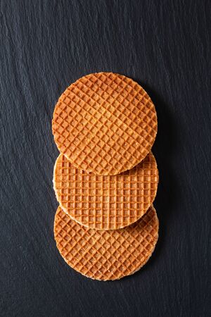 Food Concept Stroopwafel, crispy caramel syrup Dutch waffles  on black slate stone backgroundの写真素材