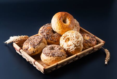 Food bakery concept Homemade organic bagels in bamboo wicker tray on black backgroundの写真素材