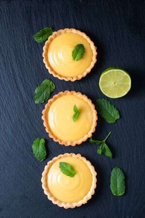 Food concept Homemade organic Lemon, lime tarts or mini pie on black slate stone boardの写真素材