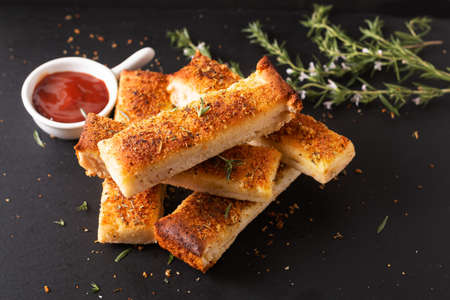 Food appetizer ideas for party concept homemade organic garlic bread stick on black slate board with copy spaceの写真素材