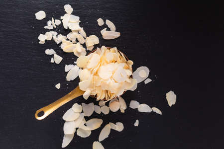 Food spices concept top view of organic slide almond in copper cup on black slate stone with copy spaceの写真素材