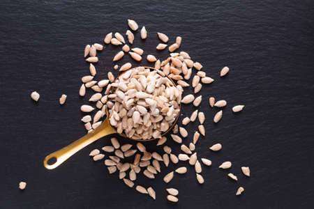Food spices concept top view of organic sunflower seed in copper cup on black slate stone with copy spaceの写真素材