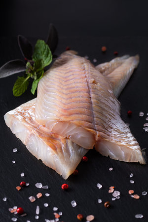 Healthy Food concept raw fillets Alaska Pollock, Black Cod on black slate stone board with copy...