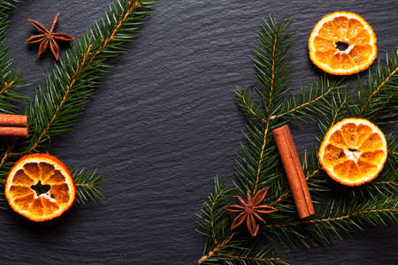Seasonal background concept Winter or Christmas spices and pine leave on black slate stone board with copy spaceの写真素材