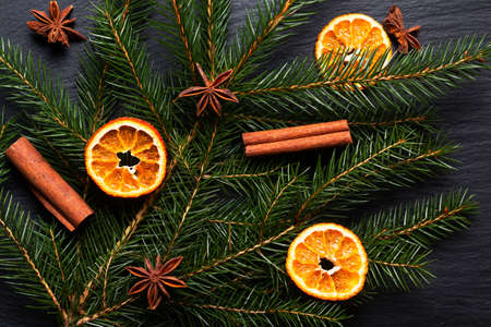 Seasonal background concept Winter or Christmas spices and pine leave on black slate stone board with copy spaceの写真素材