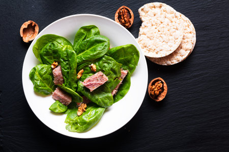 Healthy food concept Spinach salad with French Presskopf in white ceramic dish on black slate stone board with copy spaceの写真素材