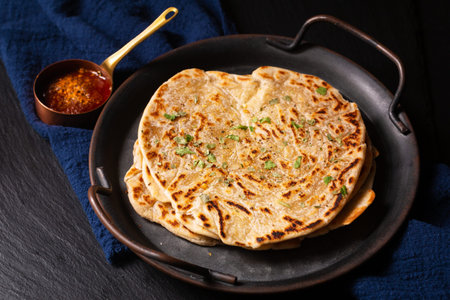 Food concept spot focus homemade Paratha, Parotta or Porotta layered flatbread  on black background...