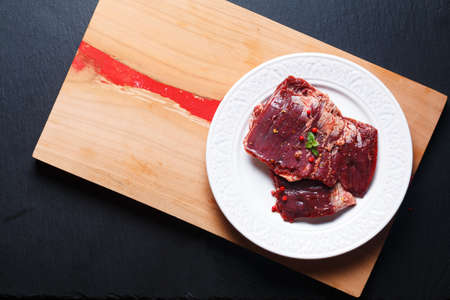 Food concept Fresh raw Skirt steak in white flat ceramic plate on wooden board and black slate stone board with copy spaceの写真素材