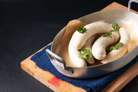 Food concept homemade organic German white sausage Weisswurst in aluminum tray on black slate stone with copy spaceの写真素材