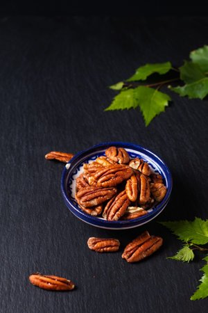 Food concept organic pecans in ceramic cup on black slate stone plate with copy space