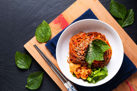 Food concept korean spicy cold buckwheat noodle Kimchi Bibim Guksu on wooden board and black background with copy spaceの写真素材