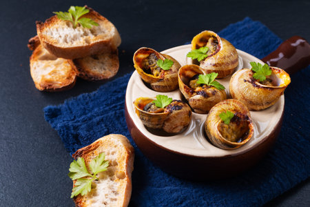 Food concept Escargots Baked French snails with Garlic butter on black slate stone background with copy spaceの写真素材