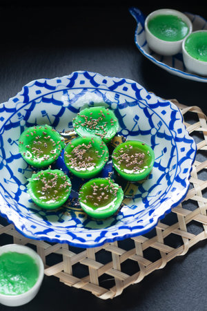 Asian food concept Thai alkaline pandan rice cake in thai pattern ceramic plate on black background with copy spaceの写真素材
