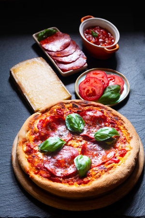 Food concept Homemade peperoni pizza with ingredients on black slate boardの写真素材