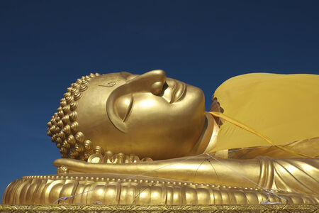A golden reclining Buddha under blue sky in old temple in Songkla Thailandの写真素材