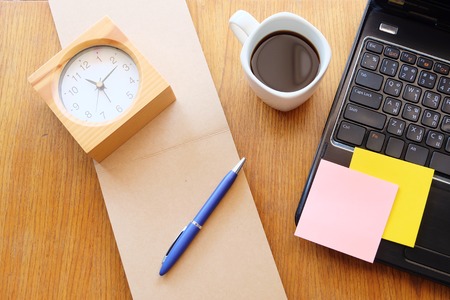 note book and laptop on wooden table with coffeeの写真素材