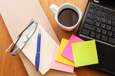 note book and laptop on wooden table with coffeeの写真素材