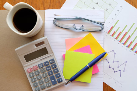 calculator and chart on the wooden table with back coffee