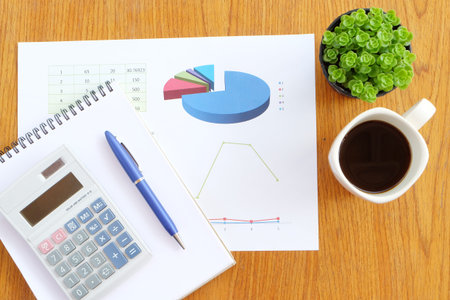 chart and calculator on the wooden table with hot coffee