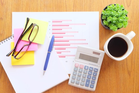 chart and calculator on the wooden table with hot coffeeの写真素材