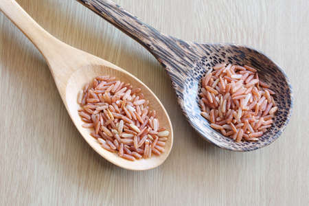 red rice on wooden spoon with wooden backgroundの写真素材