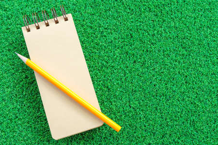 note book on green grass backgroundの写真素材