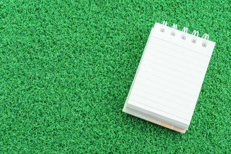 note book on green grass backgroundの写真素材