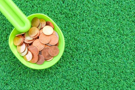coin in plastic spoon on green grass background with business conceptの写真素材